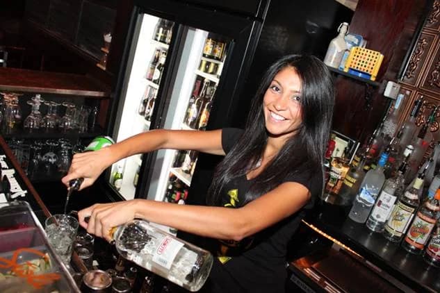 SoCal Bartender mixologist pouring a cocktail behind a fully stocked event bar
